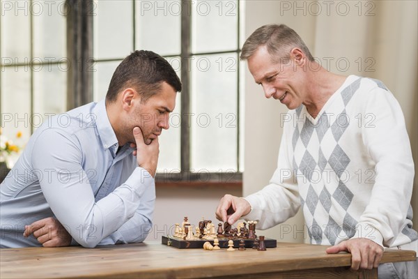 Front view father son playing chess