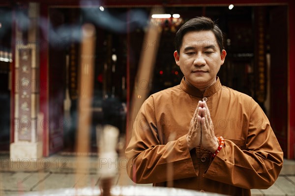 Front view man praying temple with incense