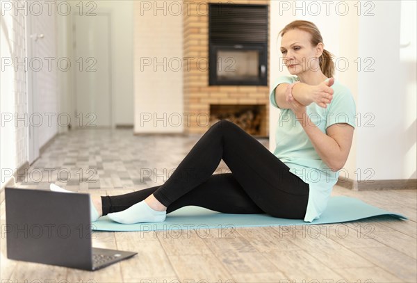 Full shot woman stretching with laptop