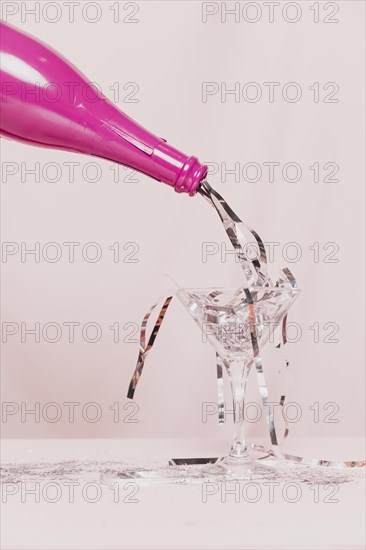 Glass filled with silver tinsel from champagne bottle