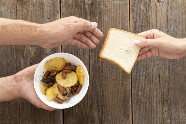 Hand giving bowl food bread needy person