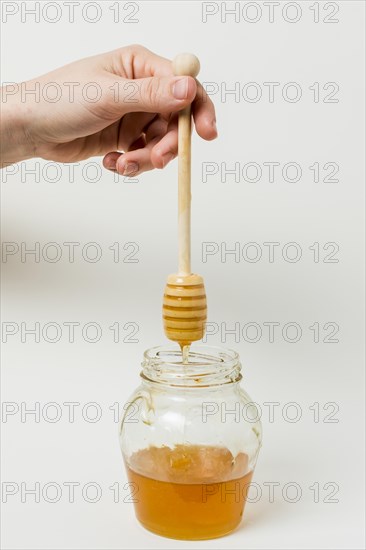 Hand holding honey spoon