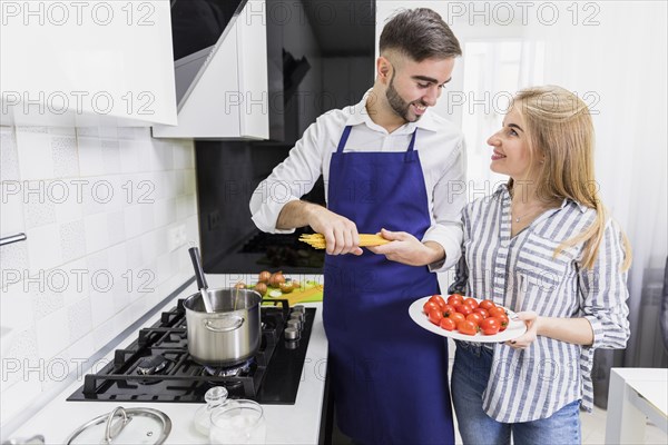 Happy couple putting spaghetti pot with boiled water