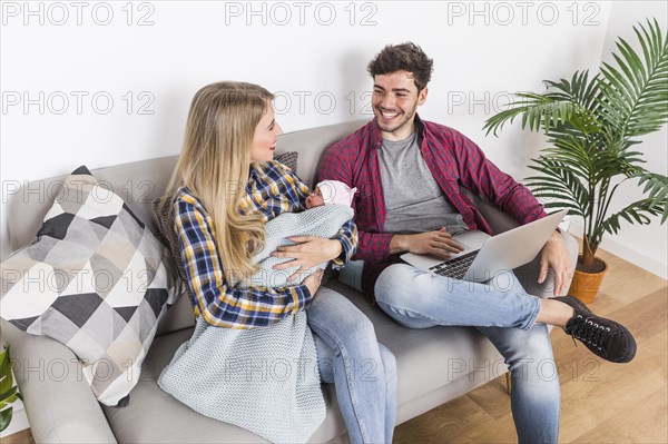 Happy parents with sleeping baby using laptop