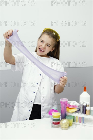 Happy young girl scientist making slime
