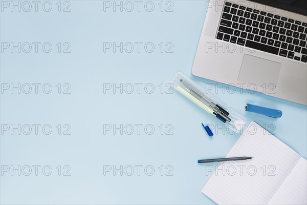 High angle view laptop stationeries blue background