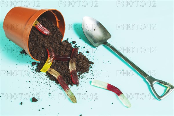 Jelly worms overturning pot with ground near shovel