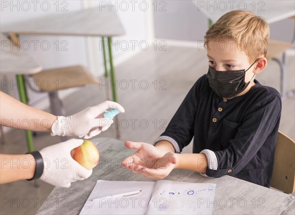 Kid disinfecting his hands before eating apple