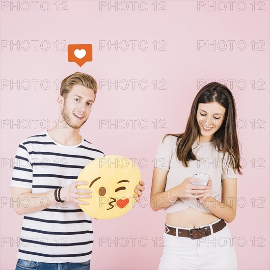 Like icon man holding kiss emoji near her girlfriend using smartphone