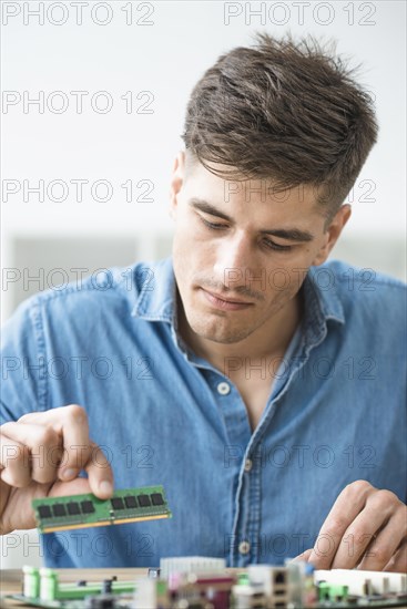 Male technician installing ram computer motherboard