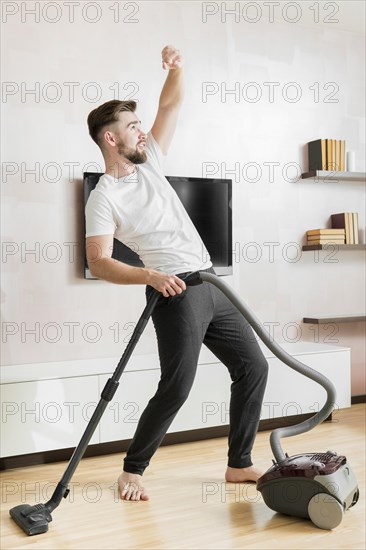 Man dancing with vacuum cleaner long shot