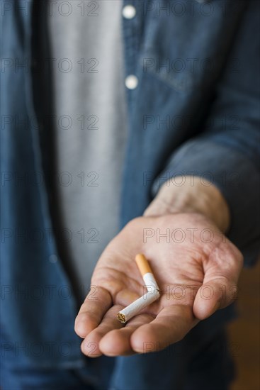 Man holding broken cigarette his hand