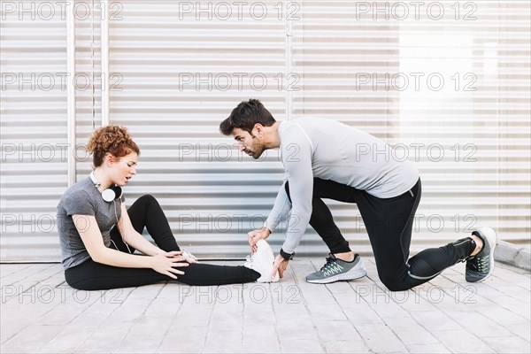 Man massaging stretched leg woman