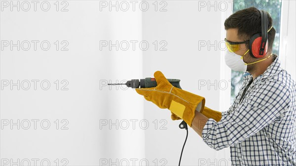 Man with safety protection equipment with drill