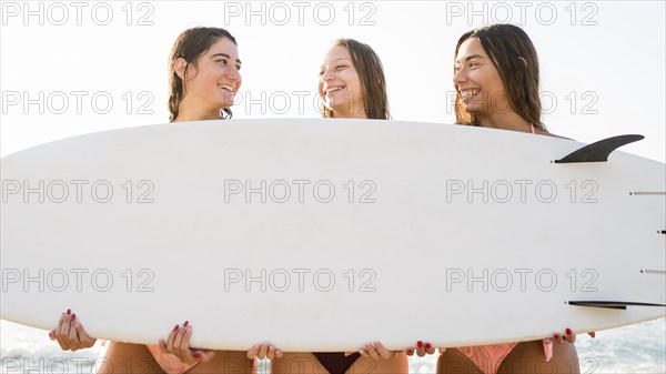 Medium shot girl friends holding surf board