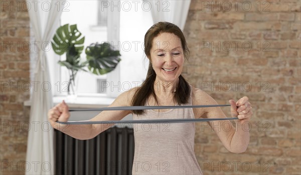 Medium shot senior woman stretching band