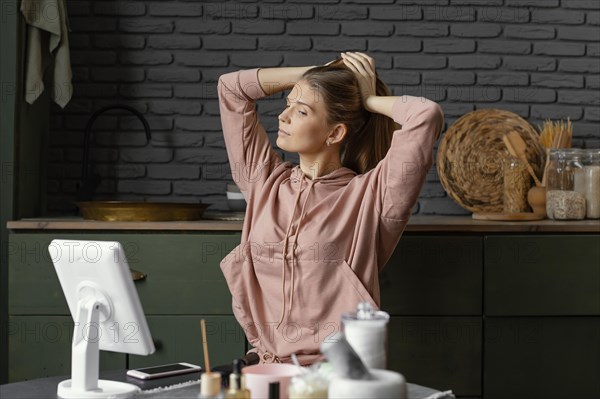 Medium shot woman tying her hair indoors