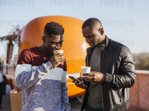 Mid shot friends enjoying coffee front food truck