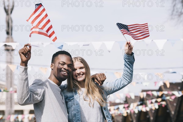 Multiethnic friends holding american flags outstretched hands