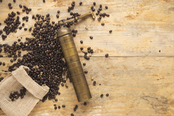 Old coffee grinder with coffee beans falling from sack table