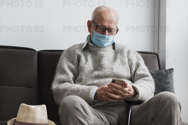 Old man with medical mask nursing home using smartphone
