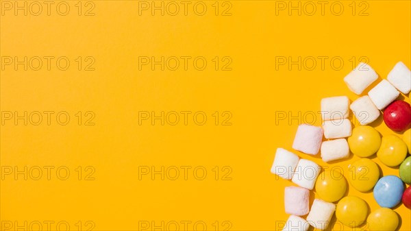 Overhead view marshmallow colorful candies yellow background