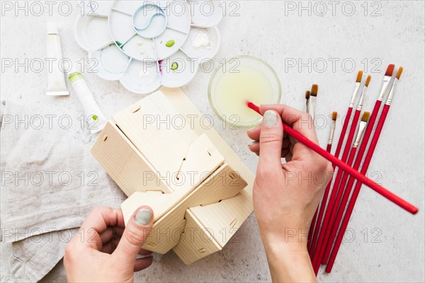 Overhead view woman s hand painting wooden house model with paintbrush