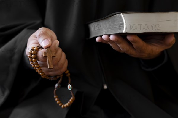 Person holding rosary with cross holy book