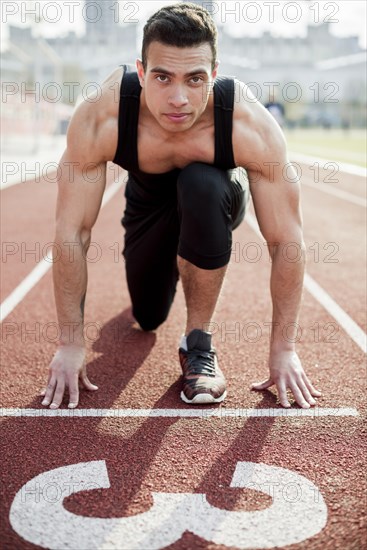 Portrait confident male athlete starting line race track