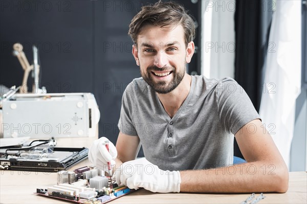 Portrait happy man repairing circuit board computer