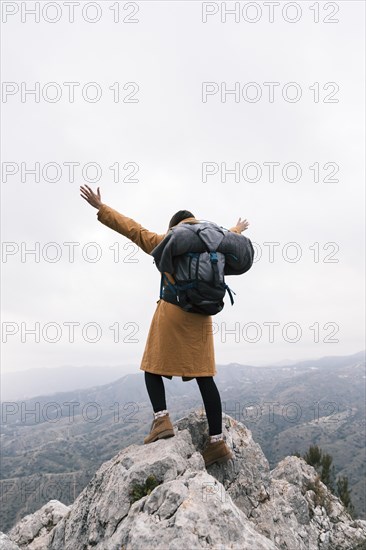 Rear view woman raising her arms standing top mountain