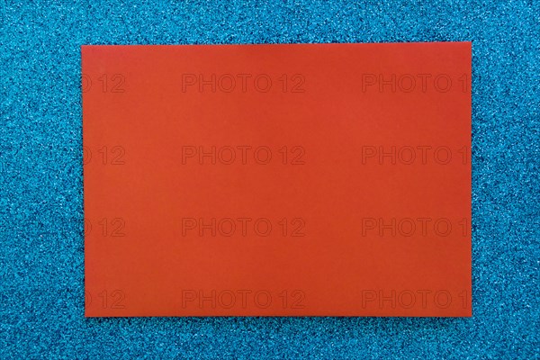 Red cardboard paper blue glitter background