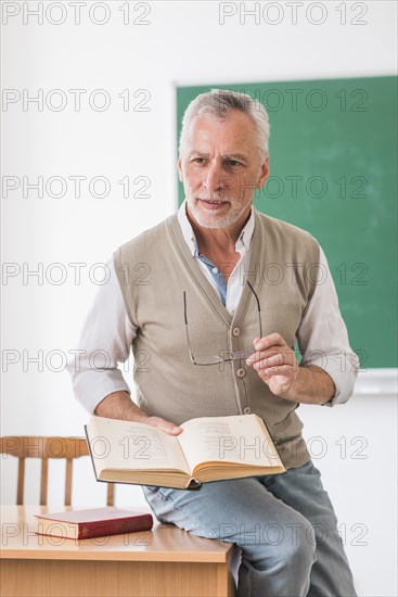 Senior professor sitting desk with book classroom