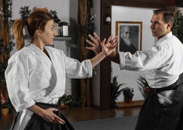 Side view male martial arts instructor practicing with female trainee