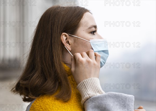 Side view woman city adjusting her medical mask