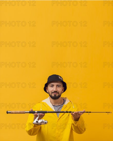 Smiley fisherman holding up fishing rod with copy space