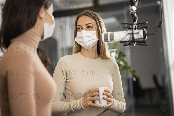 Smiley women doing radio together while wearing medical masks