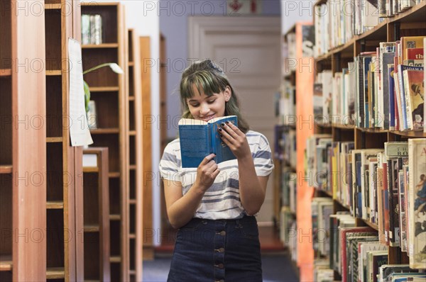 Smiling schoolgirl reading book library