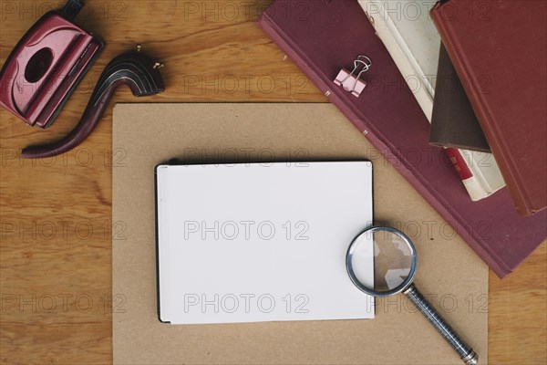 Stack books magnifying glass near notebook