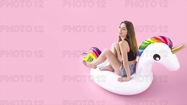 Summer fashion concept with young woman inflatable unicorn