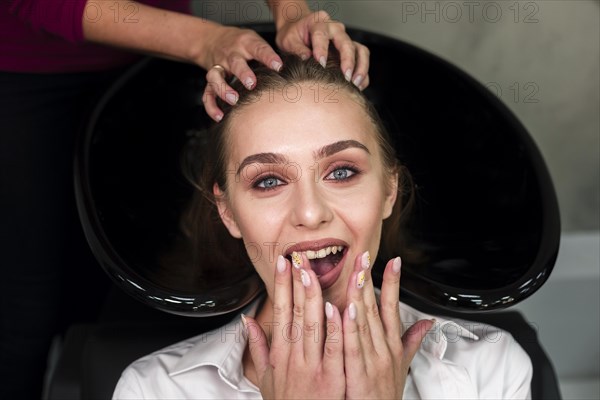 Surprised blonde woman getting hair washed