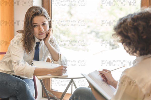Teenager doing homework near friend