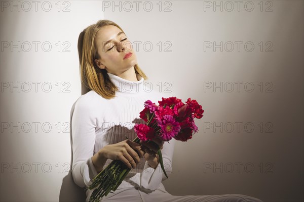 Thoughtful woman sitting with pink flowers bouquet