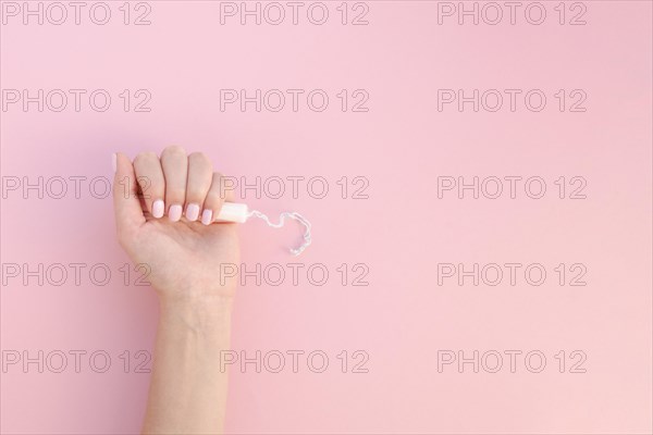 Top view hand holding tampon pink background