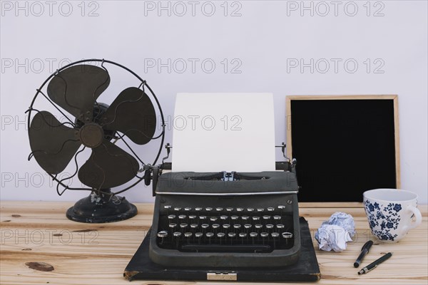 Typewriter near blackboard fan