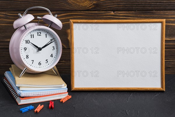 White blank board alarm clock clothes peg notebooks black desk