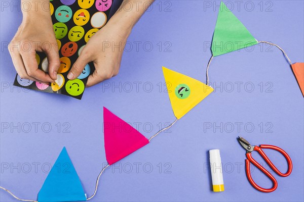 Woman hand making bunting with emoji stickers colored background