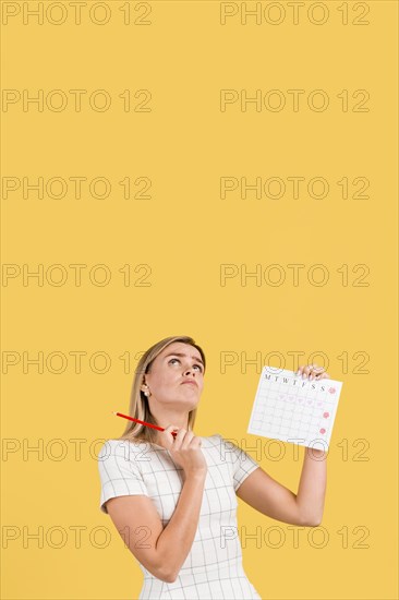 Woman looking up holding menstruation calendar with copy space