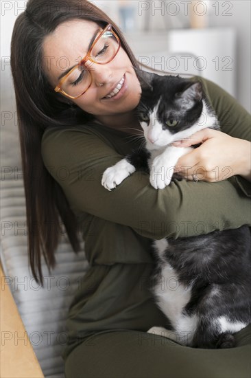 Woman playing with cat sitting chair