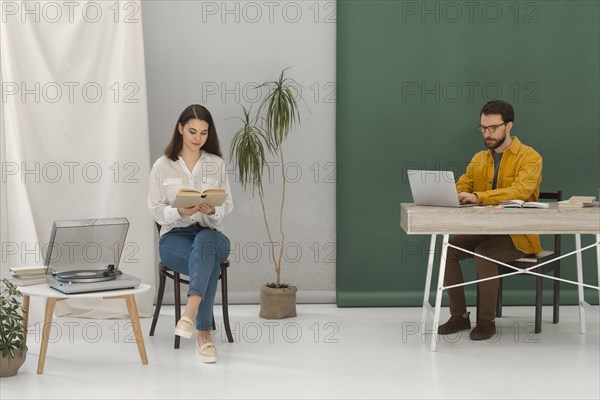 Woman relaxing while reading book man working laptop